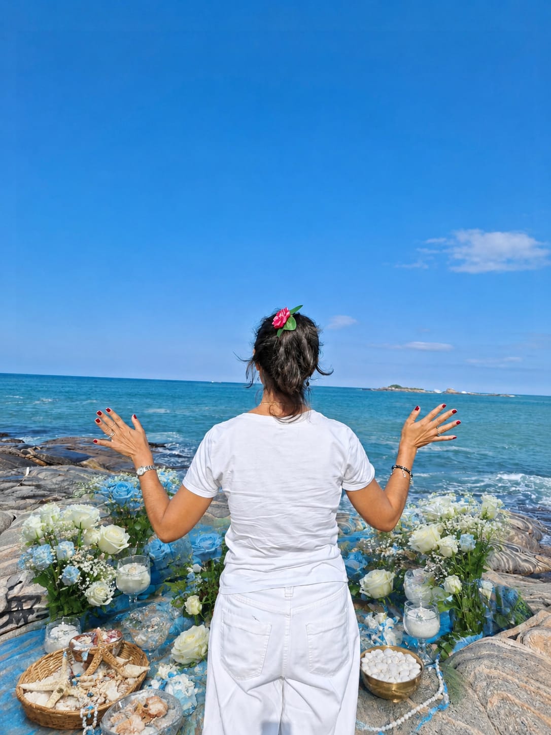 Trabalho espiritual preparado à beira-mar com flores e elementos de fé